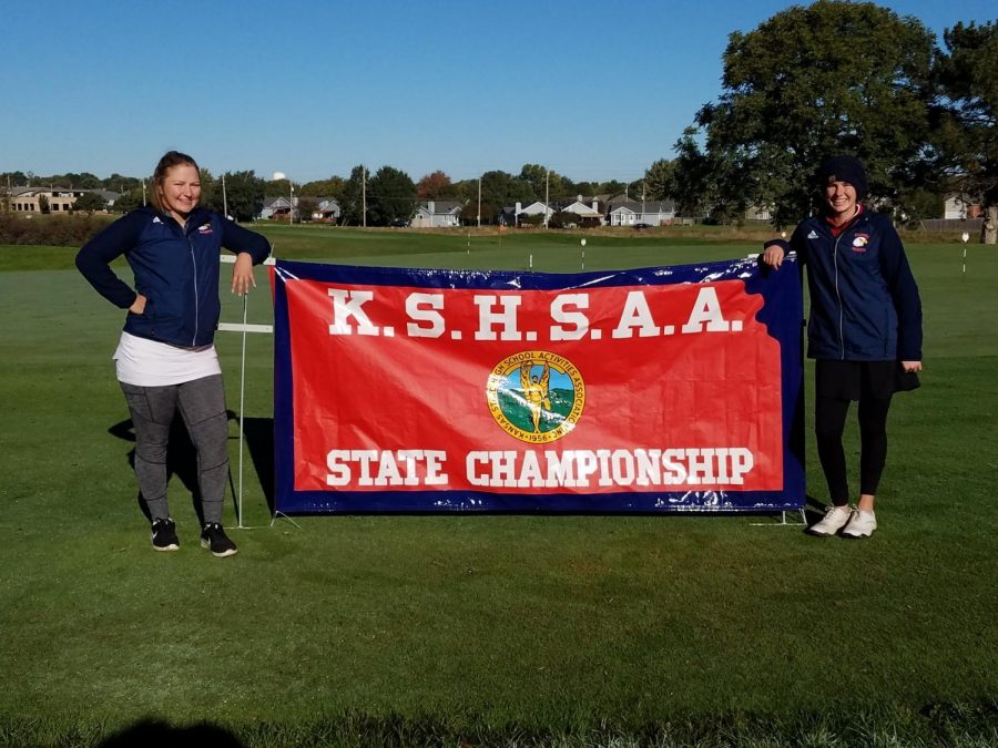 Madeline Herman and Grace Hansen pose in front of the state championship sign.